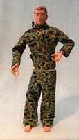 Full body image of the 1964 G.I. Joe figure in camouflage fatigues, showing articulated limbs and molded hands.