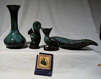 Front view showing all four Blue Mountain Pottery pieces: bud vase, squirrel, cat, and dish on white cloth