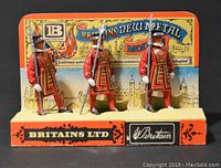 Front view of the three Britains New Metal soldier models on original branded display stand, showing colorful packaging and painted details.