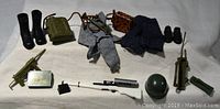 G.I. Joe lot with two pairs of boots, clothing items including pants and sweater, walkie talkie, rifle, machine gun, and other accessories arranged on white cloth
