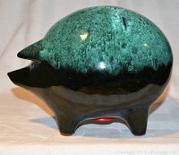 Side view of ceramic piggy bank showing two-tone glaze with blue-green mottled top and black bottom, pig shape with defined ears and snout.