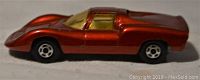 Side view of a metallic red diecast Porsche 910 car showing low wear.