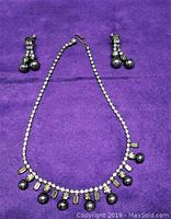 Photo showing vintage demi-parure necklace and screw back earrings on purple fabric background