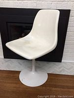 Side angle view of the vintage mid century modern tulip base swivel chair showing white seat and base with some wear and staining.
