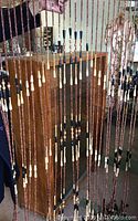 Full view showing multiple vertical strands of wood beads in light to dark tones.