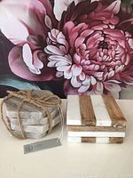 Two sets of stone coasters, one hexagonal gray stone tied with jute rope, one square with white stone and wooden strips.