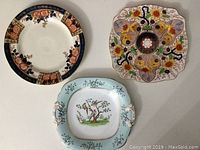 Three vintage decorative plates with different shapes and floral designs shown from the top