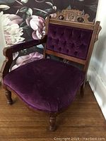 Full view of the Victorian corner chair showing dark purple velvet upholstery and the wooden armrest and legs.