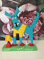 Front view of folk art dog sculpture showing bright colors and wire accessories.