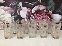 Full set of ten vintage Mid Century Modern highball glasses showing gold starburst patterns on frosted glass with gold rim.