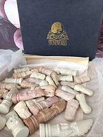Photo of stone chess pieces in natural colored shades of beige, brown, cream, and light pink with classic carved chess piece shapes.