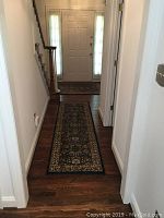 Smaller rectangular Oriental Weavers area rug runner placed in hallway, dark blue/navy floral design on hardwood floor.