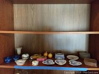 Shelf with trinket boxes, dishes, candles and glass bud vase displayed