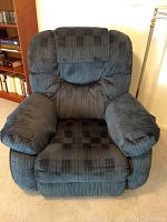 Front view of blue plush upholstered recliner chair showing padded armrests and backrest.