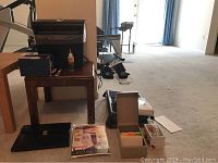 Image showing various office supplies and paper shredder items on a carpeted floor including shredder, boxes, lap desk, and small metal file.