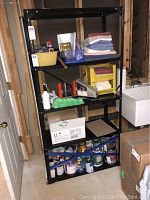 Full view of black metal shelving unit loaded with various items, showing overall size and condition.