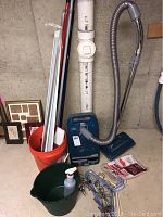 Kenmore Powermate canister vacuum cleaner, orange bucket, green bucket with white pump bottle, red mop handle, white curtain rods.