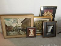 Grouping of six framed art pieces leaning against wall