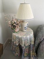 Full view of decorator table with tablecloth, lamp, and faux flowers showing overall styling and setup