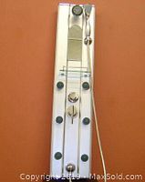 Flat stainless steel shower spa panel mounted on orange background showing multiple green spray jets, mixing controls, glass shelf, handheld wand and overhead spout