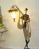 Full view of taller lamp showing metal figurine base holding scalloped mesh shade