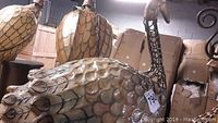 Side view of the peacock lamp showing the curved metal body with etched feather patterns and bronze metallic finish