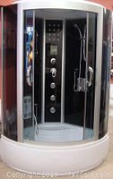 Enclosed steam shower spa unit with black interior panel and curved transparent glass doors on white base