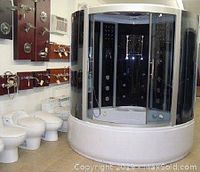 Showroom display photo of assembled shower cabin next to toilets and plumbing fixtures