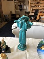 Turquoise porcelain water bearer figurine standing on a table in a living room setting