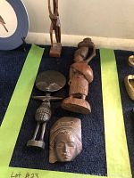 Assortment of seven African wooden figures laid out on a flat surface, including human and animal forms plus a face mask, highlighting variety, scale, and detail.