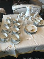 Full display of sets on table showing all items together including tea pot, plates, cups, and saucers.