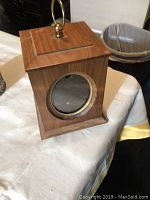 Wooden photo box with square shape, circular glass window, brass ring and handle on top