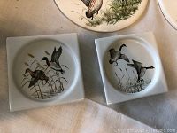 Photo of two square and round porcelain coasters with flying duck designs