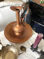 Photo of hammered copper plate with tall copper pitcher placed on top, showing the texture and handle detail