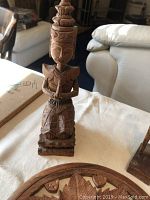 Wooden Hindu-style figurine standing in prayer pose with carved traditional dress and headpiece.