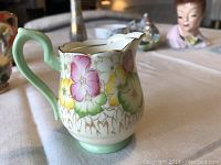 Collinwood Bone China floral creamer showing floral design, gold rim, and handle.