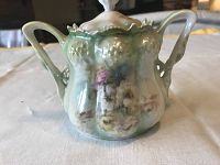 Front of Russian hand painted sugar bowl with floral motif, double handles with grape and leaf relief design, glazed green to white, visible floral painting