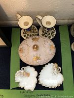 Overview of all lot items: two glass candle holders, pink floral candy dish with lid, two white ceramic cherub ring dishes in leaf and heart shapes