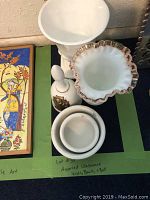 Top-down photo showing various glass vases, ceramic bell, and bowls arranged on a green surface.
