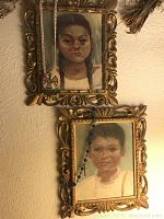 Two framed paintings of a Mexican boy and girl in ornate gold frames hanging on a wall.