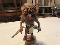Front view of carved Kachina doll showing detailed paint, feather headdress, fur beard, wooden base