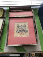 Four framed primitive batik artworks stacked with visible pink matting and metallic textured frames