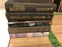 Stack of 5 hardback sci-fi books by Stephen Baxter, Jack McDevitt, and Julie Czerneda on a wooden surface.