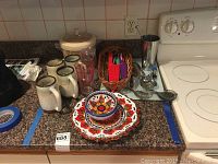 Wide view of ceramic mugs, La Maga bowls and plate, barware and other kitchen items on kitchen counter