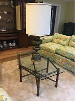 Coffee table and lamp shown in living room setting with floral patterned couches.