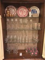 Front view of entire display showing decanter set, transferware plates and multiple types of glassware.