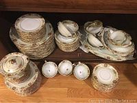 Full china set displayed stacked, including plates, bowls, cups, saucers, gravy boat, serving platters.