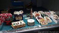 Photo of the full assortment of Christmas decor on a table including plates, nativity, ornaments, garland, candle holders.