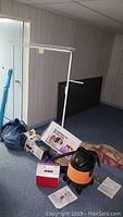 Photo showing white metal clothes rack, Shop Vac vacuum, Aero Bed bag, and other items on basement floor.
