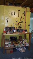 Photo of workbench against yellow pegboard wall showing hand tools hanging and various items on bench and shelf below